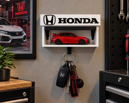 White and black Honda key holder on a garage wall with a red die-cast Honda on the shelf and keys on the hook