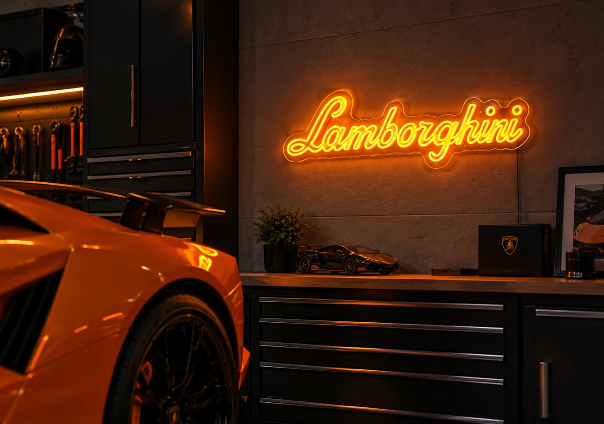 Lamborghini neon sign glowing orange on a garage wall beside an orange Lamborghini