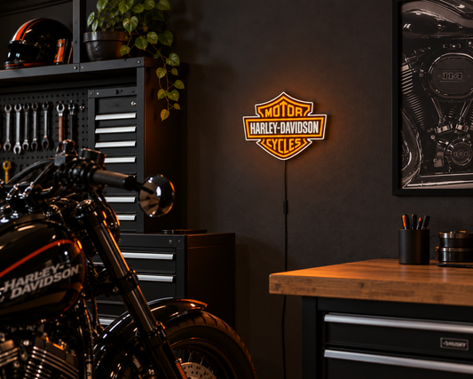 Orange and white motorcycle shield light sign glowing on a dark garage wall beside a black motorcycle and a tool cabinet