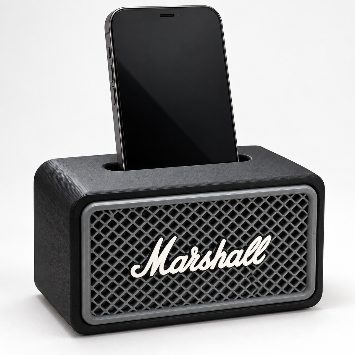Black amp-style phone speaker stand with a gray grille and script logo, holding a smartphone upright