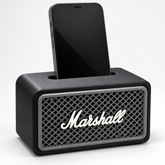 Black amp-style phone speaker stand with a gray grille and script logo, holding a smartphone upright
