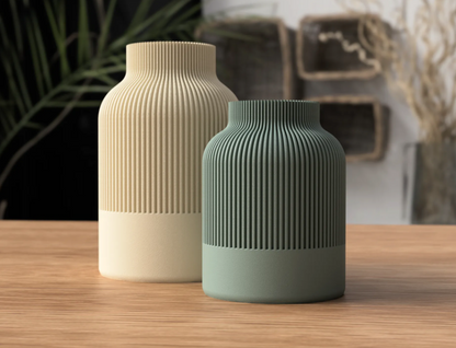 Cream and sage green ribbed vases with a smooth base on a wooden surface