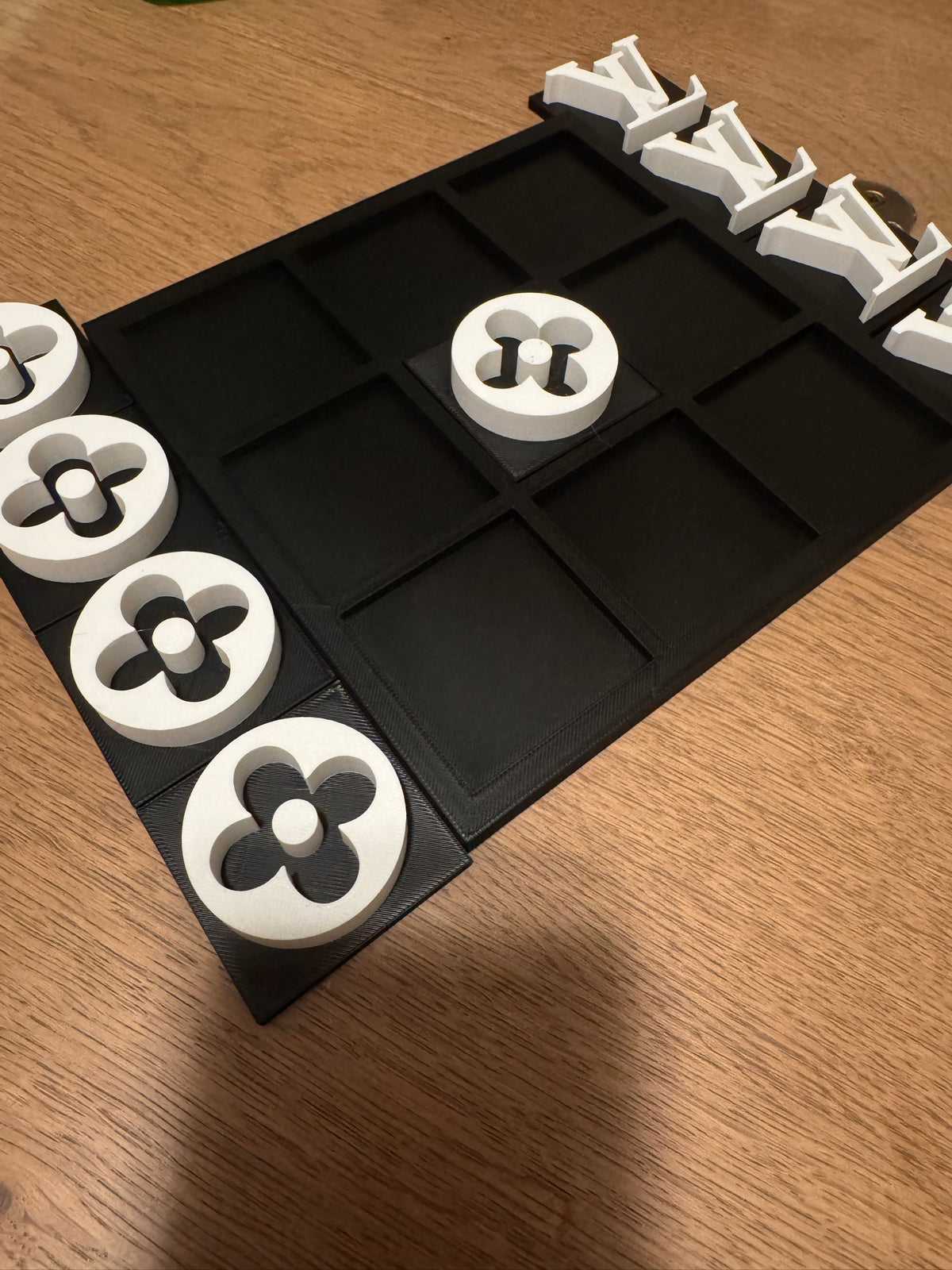 Black board with white pieces, spare pieces beside the board